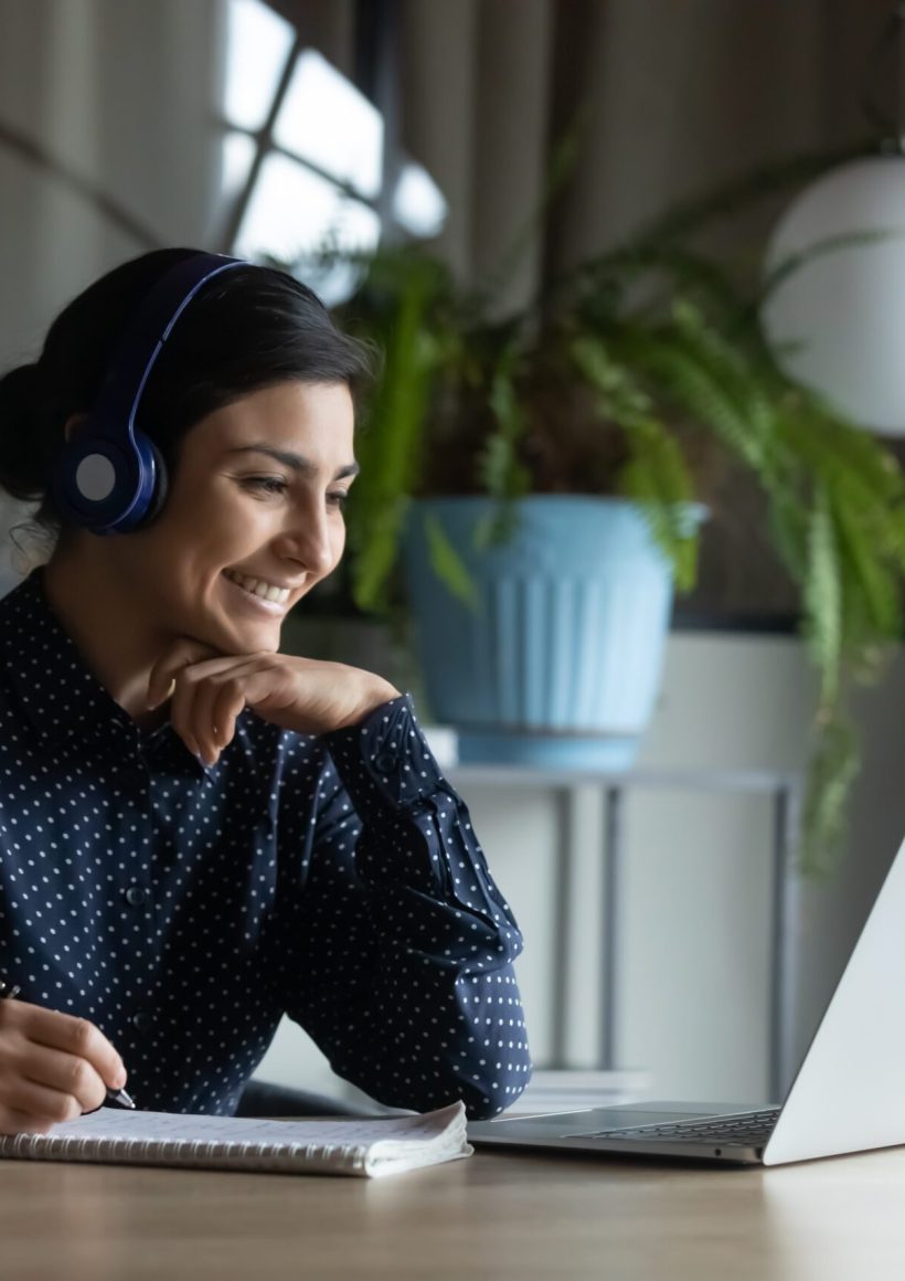 happy,young,indian,girl,with,wireless,headphones,looking,at,laptop